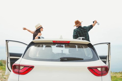 Happy travel couple enjoying freedom near SUV taking smartphone selfie make memories having fun at