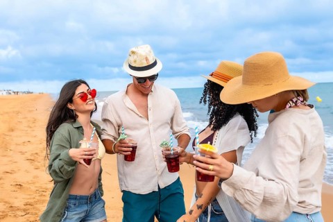 Group of young friends celebrating and having fun on a summer beach vacation, walking along the