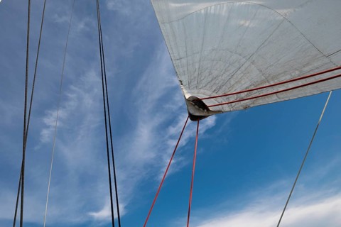 View of sails and ropes of a sailing ship against a blue cloudy sky, Aeolian or Lipari Islands,