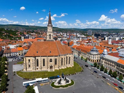 Historic church with red roof surrounded by city buildings under blue sky, aerial view, St.