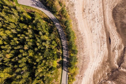 Aerial view of a winding road on the edge of a wooded area and dry areas, emptied Schwarzenbach
