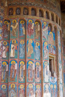 Wall with holy figures on magnificent frescoes in blue and red accents, exterior view, Saint George