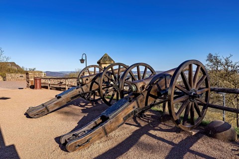 Two historic cannons on a sandy path with a view under a clear blue sky, The cannons on the