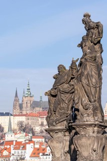 Sculpted historical figures stand prominently with the iconic Prague Castle sprawling in the