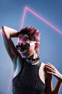 A striking cyberpunk woman model wearing reflective sunglasses and bold accessories. Her edgy