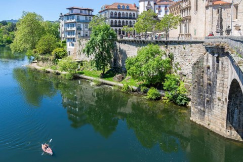 Person kayaking in River Tamega next to historic town centre, Amarante, Portugal