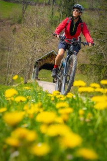 Pretty senior woman riding her electric mountain bike in early springtime in the Allgau mountains,