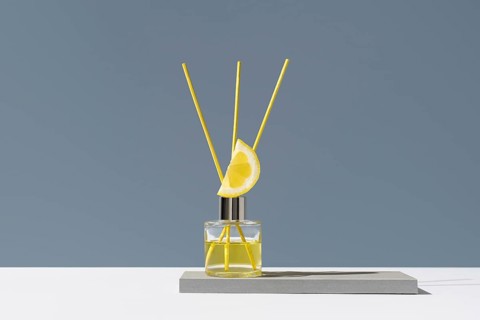 Elegant glass diffuser with lemon slice and floral motif. Yellow reeds release a refreshing citrus