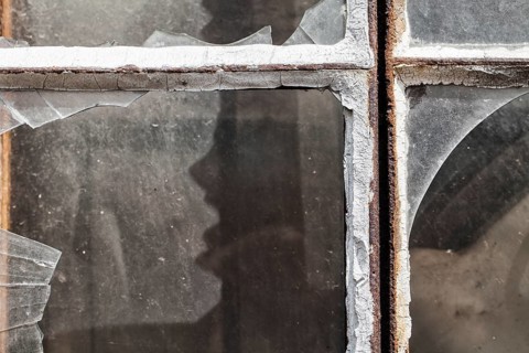 Broken window panes with a human-like screaming face