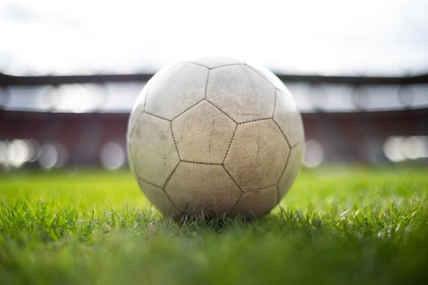 White soccer ball lying on the grass at stadium in Lubin, Poland