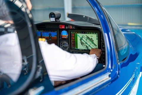 Pilot is adjusting the advanced instrument panel showing a detailed airport map, focusing on
