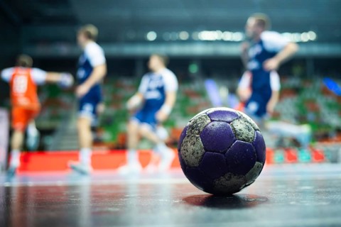 The handball ball laiyng on the parquet and handball match in the background in Lubin, Poland