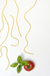 Individual spaghetti and tomato with basil, concept image
