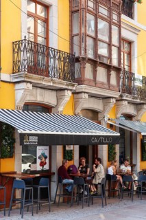 People enjoys the terrace of a bar in a sizzling day, Llanes village, principality of Asturias,