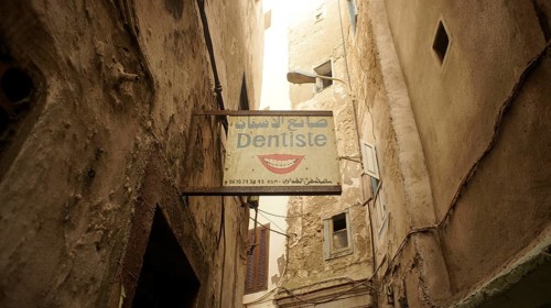 A narrow alley with a sign from a dentist between old, mysterious buildings in the old town, Medina