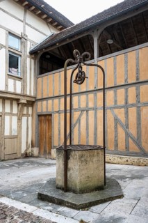 Historic well with delicate wrought iron wheel construction in the old town of Troyes, Aube