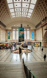 Large station concourse with impressive architecture and numerous people in an urban environment,