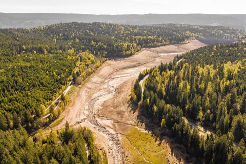Aerial view of a dry riverbed surrounded by autumnal forests, emptied Schwarzenbach dam, Forbach,