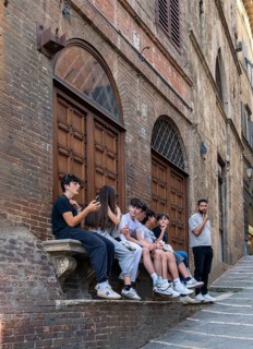 Group of teenagers sitting on a stone bench in Piazza del Campo, Siena, Tuscany, Italy