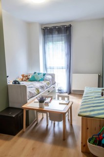 Bright kids' bedroom showcasing a comfortable bed with storage drawers, a small wooden activity