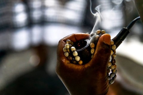A woman's hand holding a rosary and a pipe with smoke coming out of it, Belo Horizonte, Minas