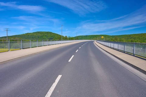 Empty road Mainbrücke in a rural landscape with wide skies and green hills, Gemünden am Main,