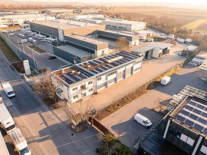 Industrial complex with solar roofs and warehouse buildings, surrounded by roads in the morning,