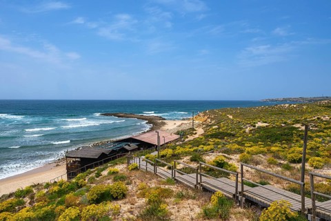 Coastal view of a secluded beach with cliffs and a wooden promenade, Vila Nova de Milfontes, Beja,