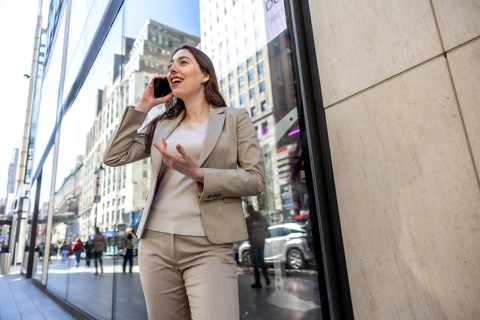 Businesswoman walking on a building lined street in manhattan, new york while speaking on her
