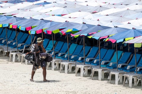 Beach vendor in front of empty sun loungers, Koh Larn, Thailand