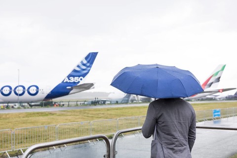 A visitor holding an umbrella in front of an Airbus A360 at the ILA (International Aerospace