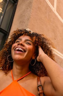Young black woman with curly hair expressing genuine happiness and joy while laughing outdoors