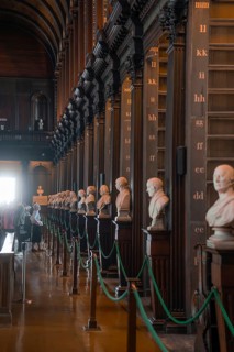 Row of busts along the pillars of a wooden library, people traveling, Trinity Collage, Dublin,