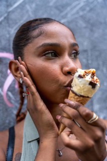 Young woman eating a sweet ice cream cone, experiencing pleasure and refreshment on a hot day, with