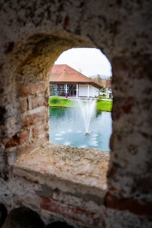 A pond with fountain in front of a building viewed through an arched window, Isny, Allgäu, Bavaria,