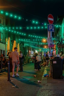 People on a street lit by green lights at night with lively atmosphere, nightlife, Dublin, Ireland