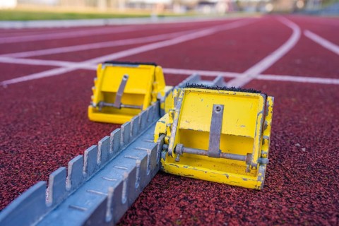 Two yellow starting blocks on a red track, ready for the next challenge