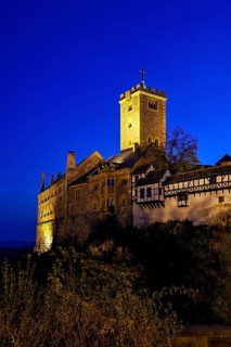 Illuminated castle at night with a visible tower and mysterious atmosphere, The Wartburg near
