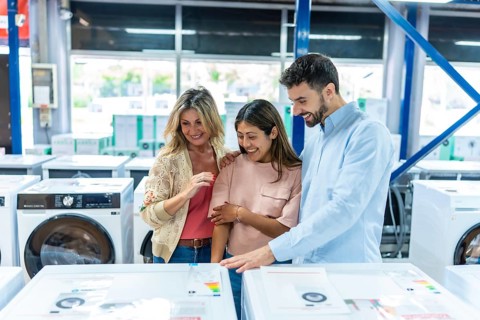 Happy family exploring washing machines and other household electronics, smiling and discussing