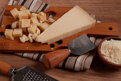 Freshly sliced and grated cheese, parmesan cheese, Gran gusto. Grana padano. on a wooden chopping