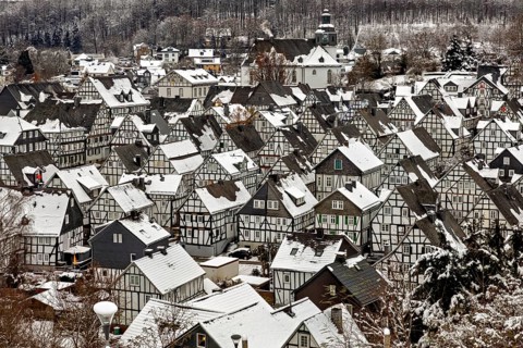 Snowy village with half-timbered houses and church, surrounded by wintry forest, The historic
