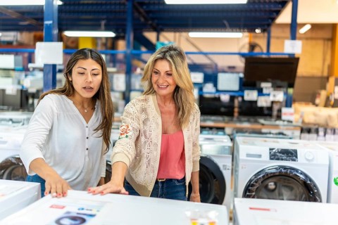 Mother and daughter shopping for electric appliances, comparing models and features in a home
