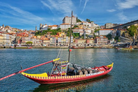 Rabelo boat on the Douro River by Porto Ribeira, Portugal, with wide riverfront skyline and wine
