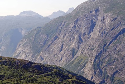 Extensive view of impressive rock formations and green valleys and a gravel road in the fells,
