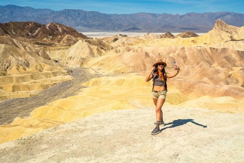 Happy young woman adventurer enjoying desert landscape at zabriskie point in death valley national
