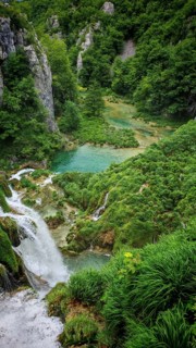 Waterfall flows into a clear lake surrounded by lush nature, Plitvice Lakes National Park, Croatia