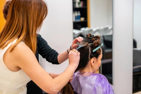 Professional hairdresser carefully applying color treatment to a customer's hair, a process of