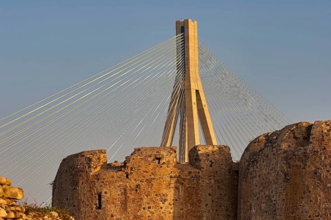Detailed view of a modern bridge behind old castle walls in the warm light of the evening sun,