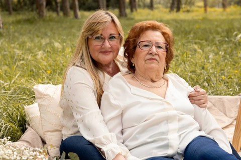 A mother and daughter share a loving moment in a serene outdoor setting. Sitting together on a soft