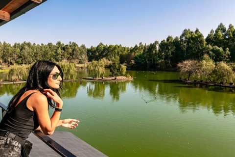 Caucasian woman on viewpoint platform looks right with green nature and lake in the background.